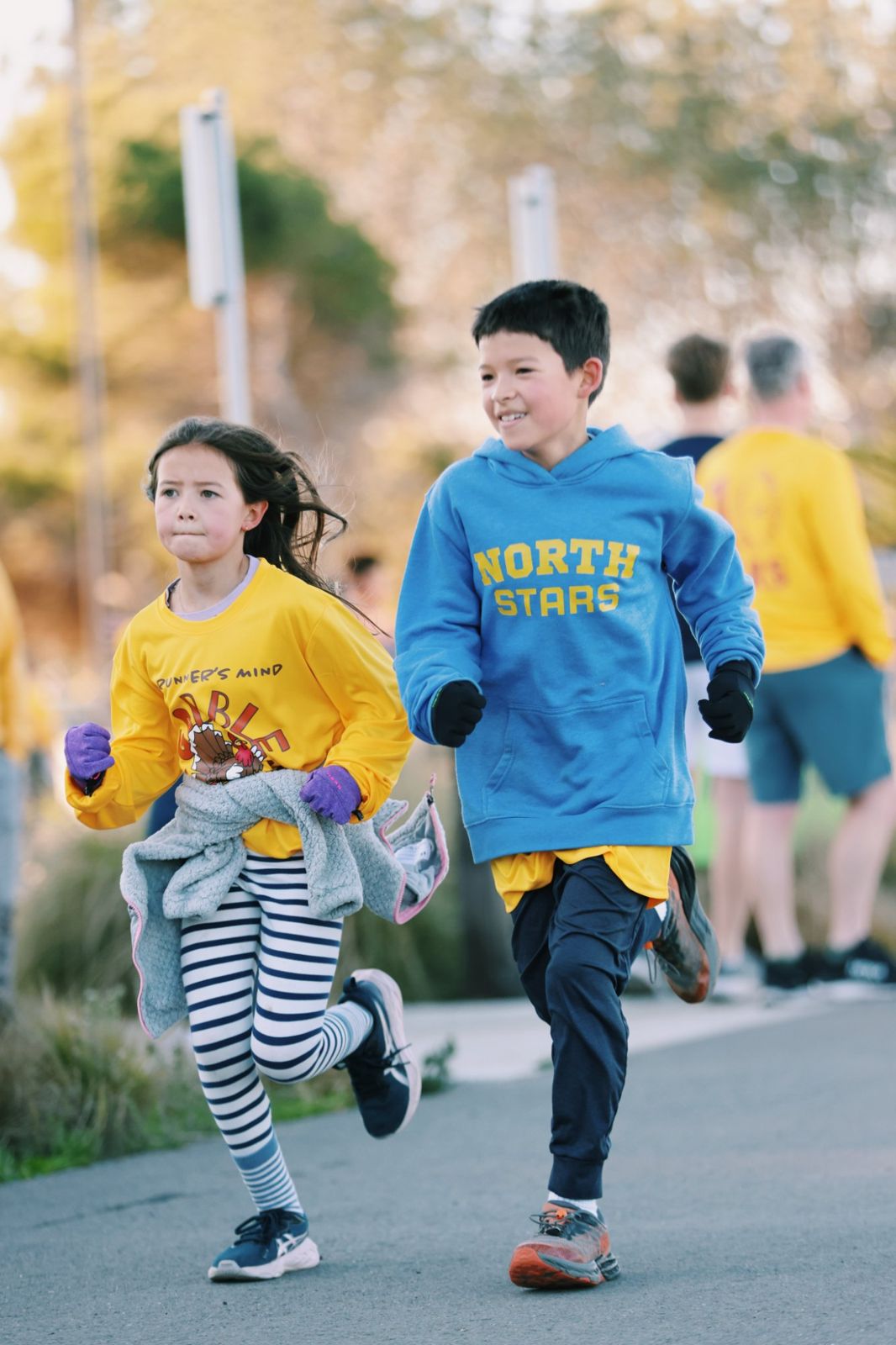 Two kids running side by side on the course