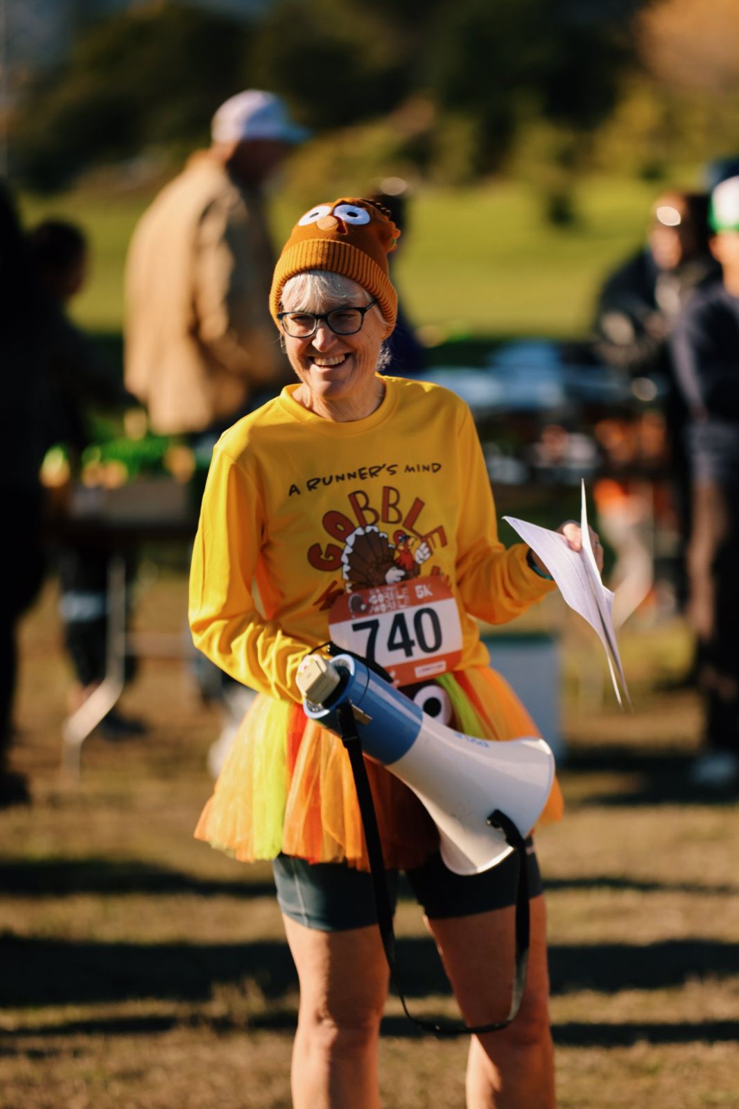 Smiling runner in a turkey beanie and tutu holding a megaphone